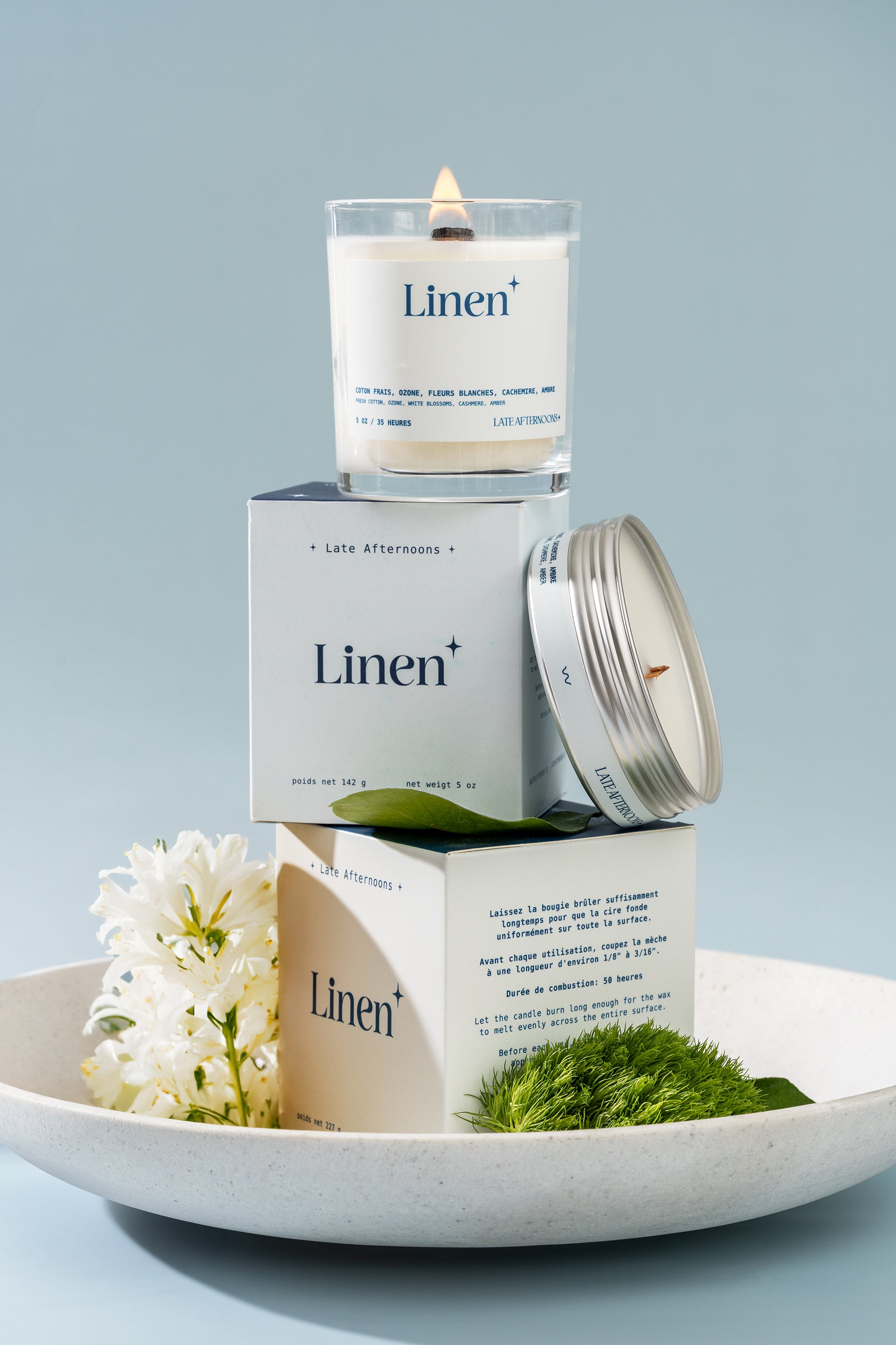 Candle labeled 'Linen' with packaging and decorative elements on a light blue background