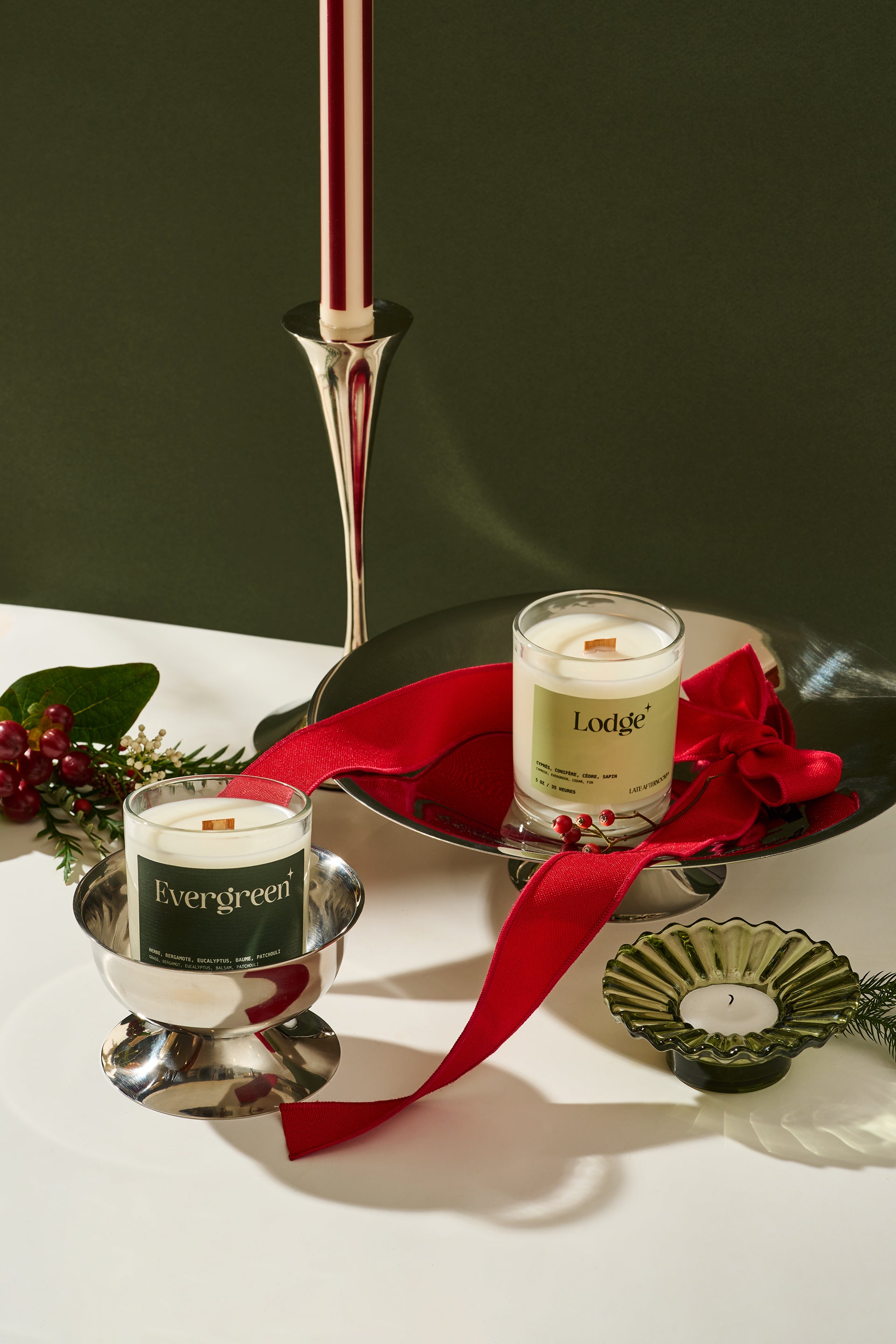 Decorative candles with red ribbon on a white surface against a dark background
