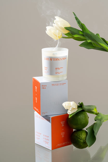 Doux Mist candle on stacked boxes with white tulips and lime, coconut soy candle by Late Afternoons